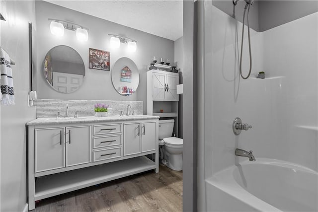 full bathroom with hardwood / wood-style flooring, backsplash, shower / bathing tub combination, vanity, and toilet