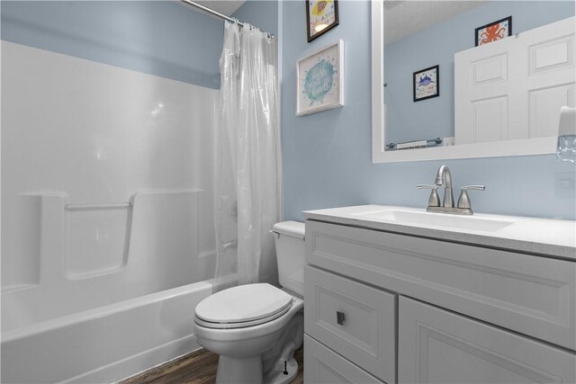 full bathroom featuring toilet, hardwood / wood-style floors, vanity, and shower / tub combo with curtain