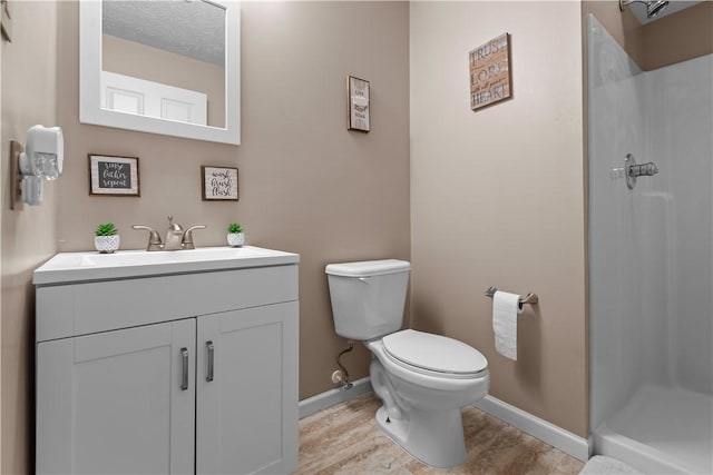 bathroom featuring walk in shower, vanity, wood-type flooring, and toilet