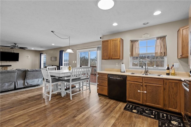 kitchen with dishwasher, sink, hanging light fixtures, hardwood / wood-style flooring, and a textured ceiling