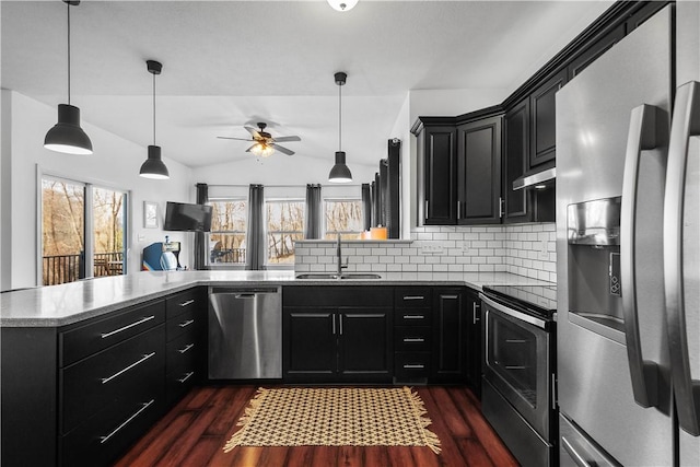 kitchen featuring sink, dark hardwood / wood-style floors, kitchen peninsula, decorative backsplash, and appliances with stainless steel finishes