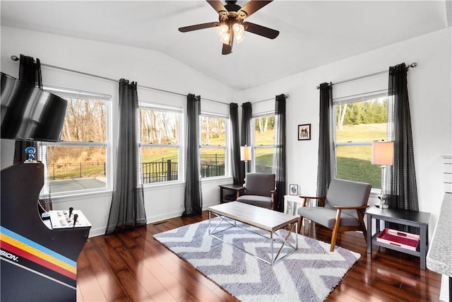 living area with ceiling fan, dark wood-type flooring, a healthy amount of sunlight, and vaulted ceiling