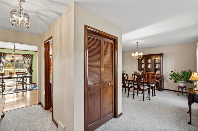 hallway with light colored carpet and a chandelier