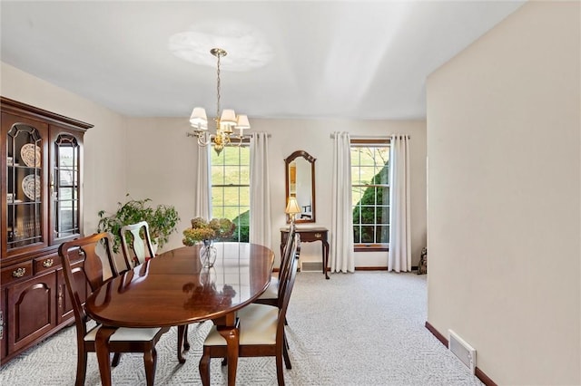 dining room featuring light carpet and a chandelier