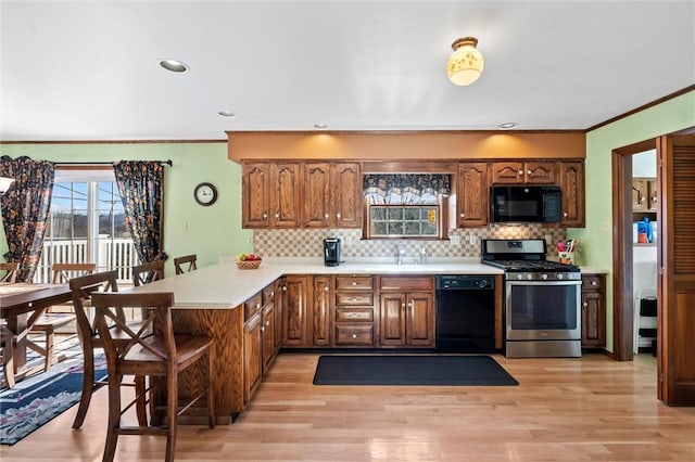 kitchen featuring kitchen peninsula, light hardwood / wood-style flooring, ornamental molding, and black appliances