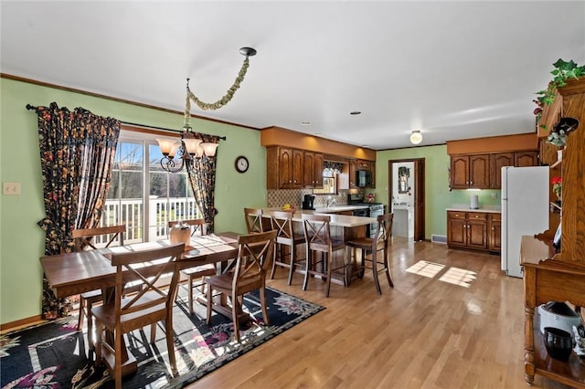 dining area featuring a chandelier, light hardwood / wood-style floors, ornamental molding, and sink