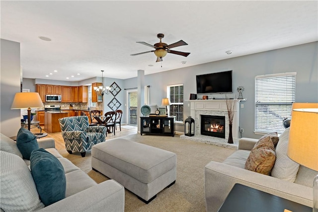 carpeted living room featuring ceiling fan with notable chandelier