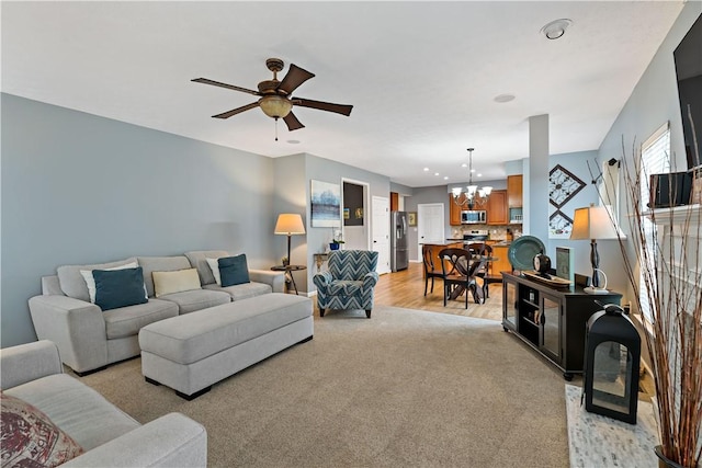 carpeted living room featuring ceiling fan with notable chandelier