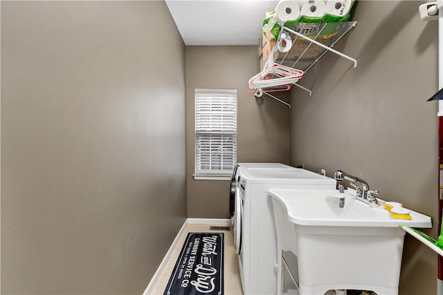 washroom featuring tile patterned floors, sink, and washing machine and clothes dryer