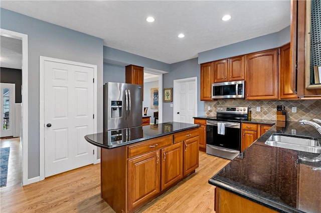 kitchen featuring sink, a center island, stainless steel appliances, tasteful backsplash, and light wood-type flooring