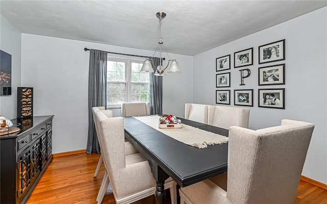 dining space with wood-type flooring and an inviting chandelier