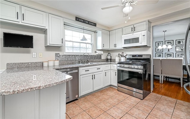 kitchen featuring appliances with stainless steel finishes, sink, decorative light fixtures, white cabinets, and light tile patterned flooring