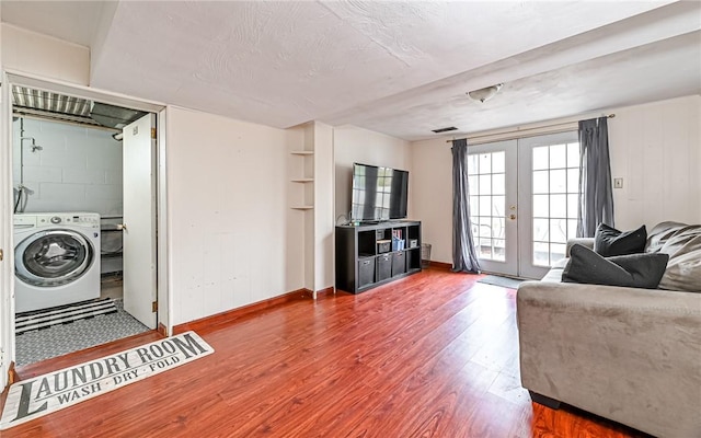 living room with hardwood / wood-style flooring, washer / dryer, a textured ceiling, and french doors