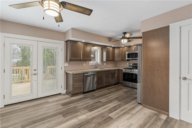 kitchen with appliances with stainless steel finishes, light wood-type flooring, french doors, ceiling fan, and sink