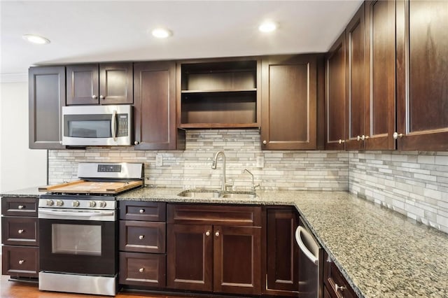 kitchen with appliances with stainless steel finishes, backsplash, light stone counters, and sink