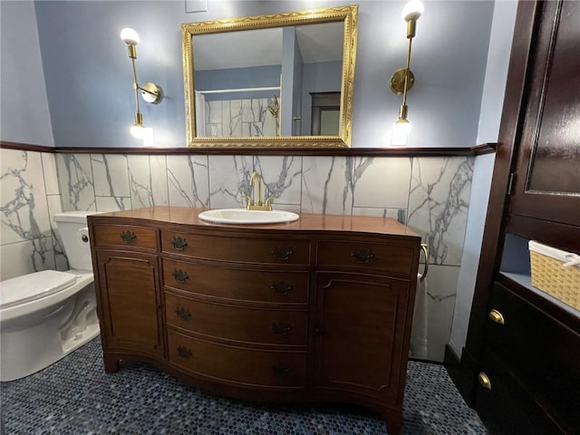 bathroom featuring tile patterned flooring, vanity, toilet, and tile walls