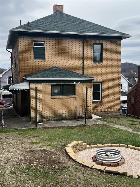 rear view of property featuring a fire pit