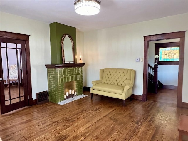 sitting room with baseboards, wood finished floors, a fireplace, and visible vents