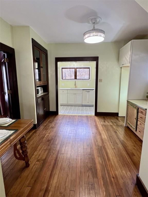 unfurnished dining area featuring a sink, baseboards, and dark wood finished floors