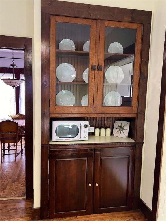 interior details featuring white microwave, wood finished floors, and baseboards