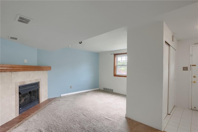 unfurnished living room featuring a tiled fireplace and light carpet