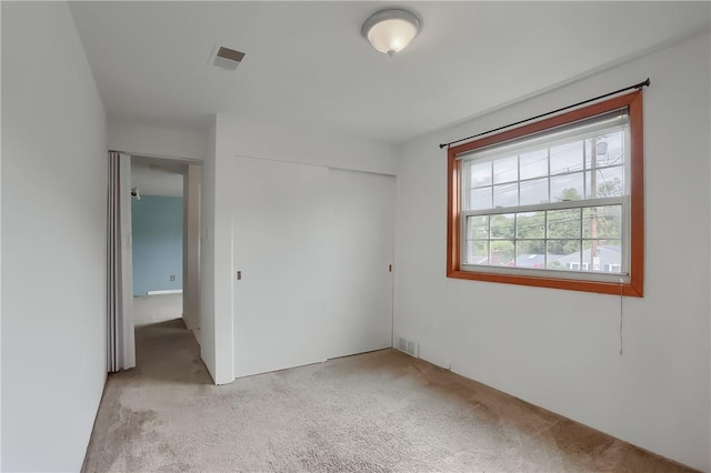 unfurnished bedroom with a closet and light colored carpet