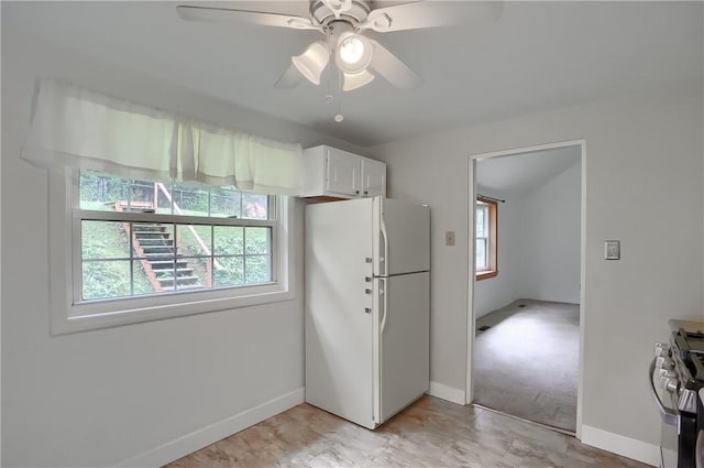 kitchen with white cabinets, white fridge, plenty of natural light, and stainless steel range oven