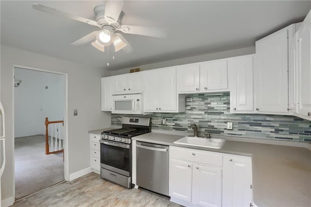 kitchen with backsplash, stainless steel appliances, ceiling fan, sink, and white cabinets