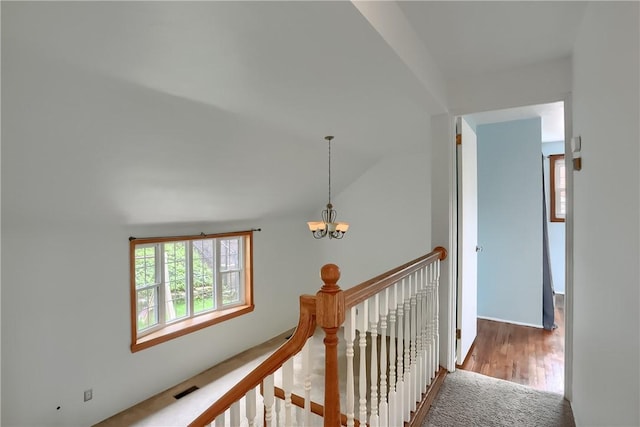 hall with carpet, vaulted ceiling, and a notable chandelier