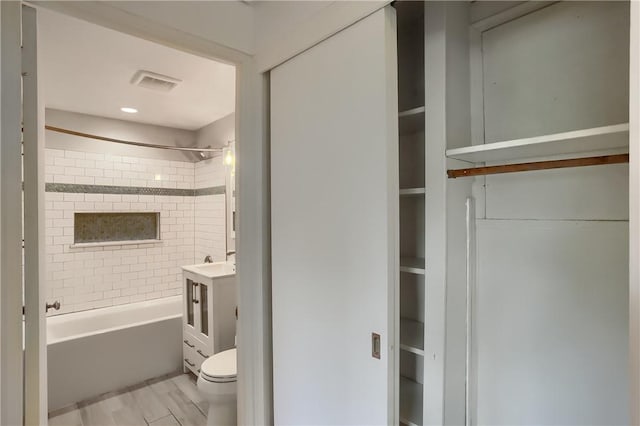 full bathroom with vanity, wood-type flooring, tiled shower / bath combo, and toilet