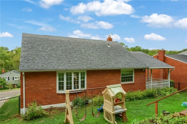 rear view of property featuring a lawn and a playground