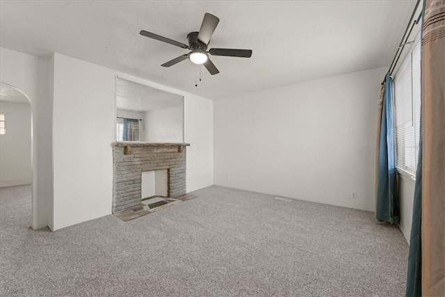 unfurnished living room with a brick fireplace, ceiling fan, and a healthy amount of sunlight