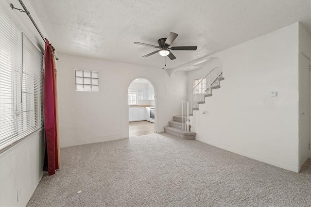 unfurnished room with ceiling fan, a textured ceiling, and light carpet