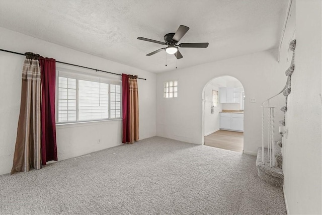 unfurnished room featuring a textured ceiling, ceiling fan, and light carpet