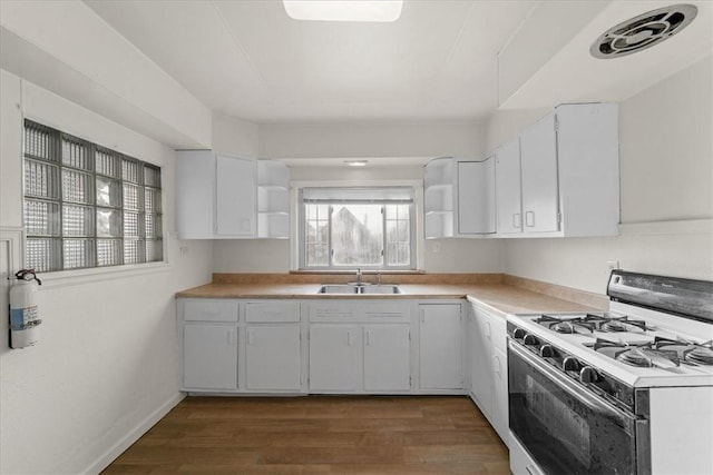 kitchen featuring white cabinets, dark wood-type flooring, gas range gas stove, and sink