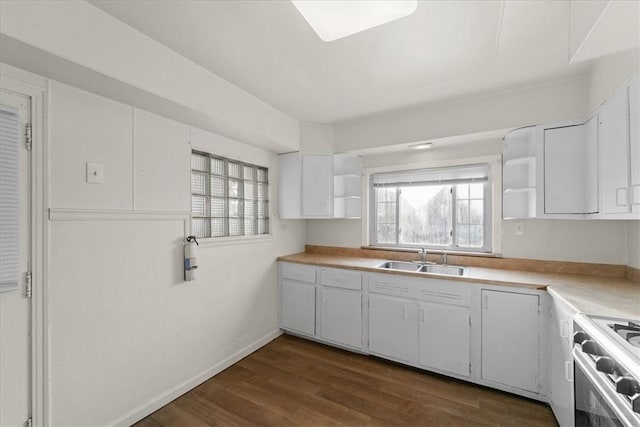 kitchen with dark hardwood / wood-style flooring, stove, white cabinetry, and sink