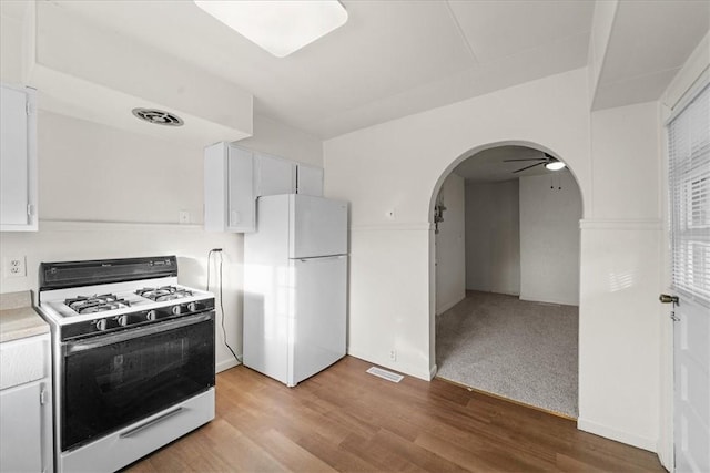 kitchen featuring ceiling fan, white cabinetry, light colored carpet, and white appliances