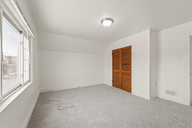 carpeted empty room with vaulted ceiling