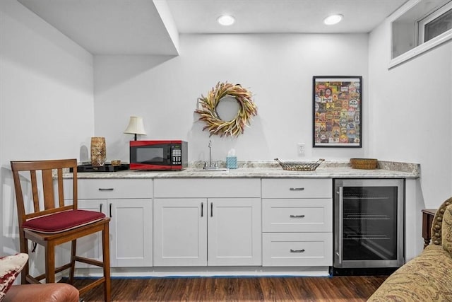 bar featuring white cabinets, dark hardwood / wood-style flooring, sink, and beverage cooler