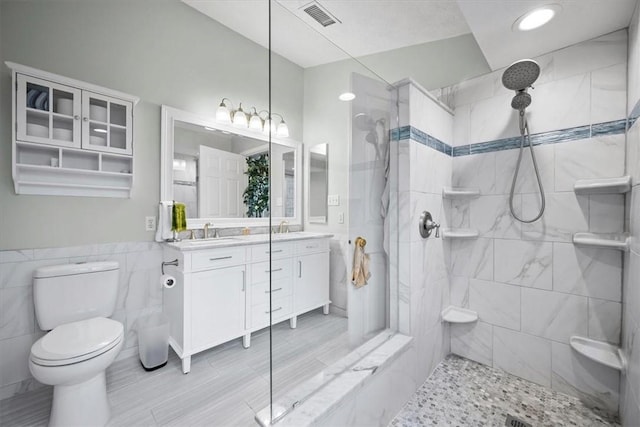 bathroom featuring vanity, toilet, and tiled shower