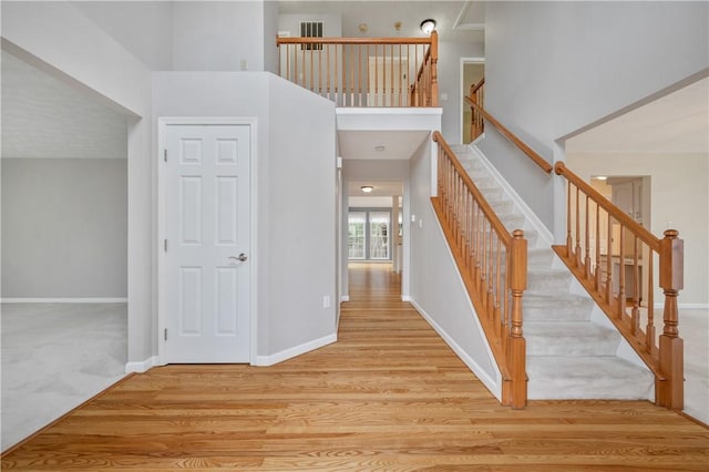 stairs with wood-type flooring and a high ceiling