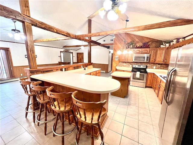 kitchen featuring a breakfast bar, stainless steel appliances, a kitchen island, and wooden walls