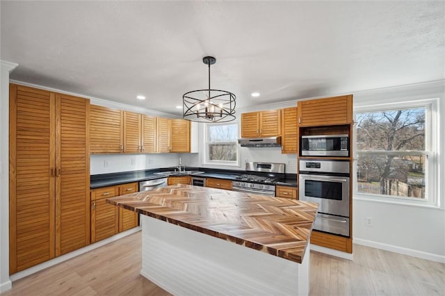 kitchen featuring ornamental molding, stainless steel appliances, decorative light fixtures, a chandelier, and butcher block counters