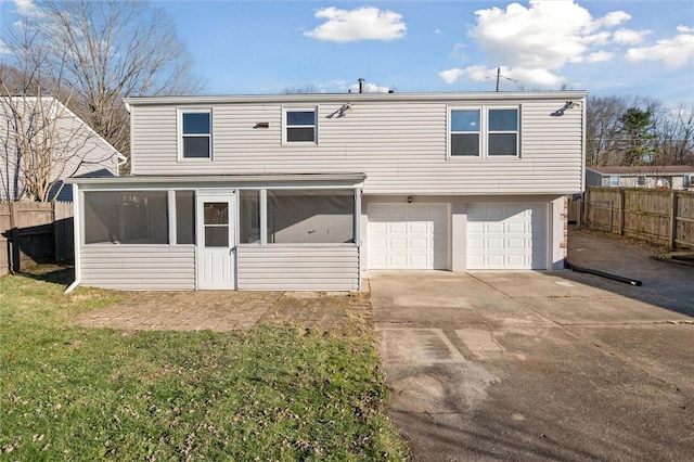 view of front of home with a sunroom, a front lawn, and a garage