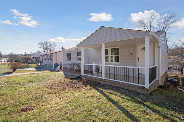 view of front of property featuring covered porch, central AC, and a front yard