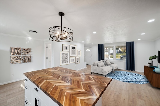 living room featuring light wood-type flooring, crown molding, and a chandelier