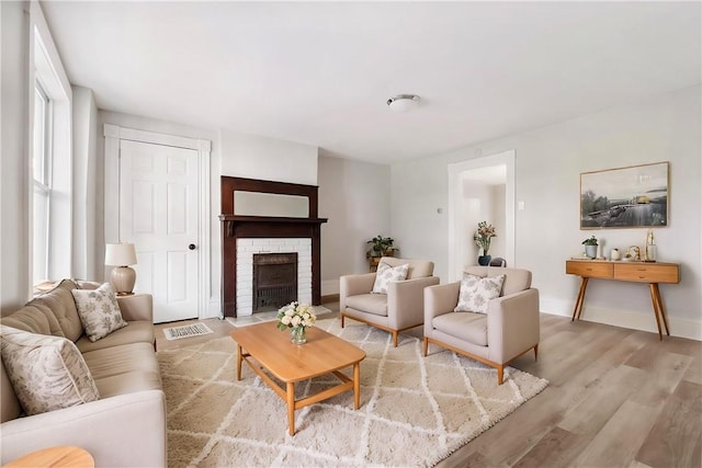 living room featuring light hardwood / wood-style flooring and a brick fireplace