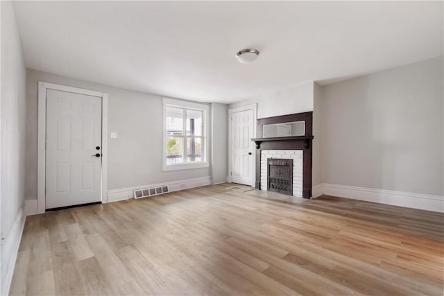 unfurnished living room with light hardwood / wood-style floors and a brick fireplace