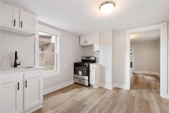 kitchen featuring gas range, white cabinetry, sink, and light hardwood / wood-style flooring