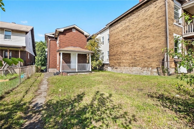 back of property featuring a porch and a yard